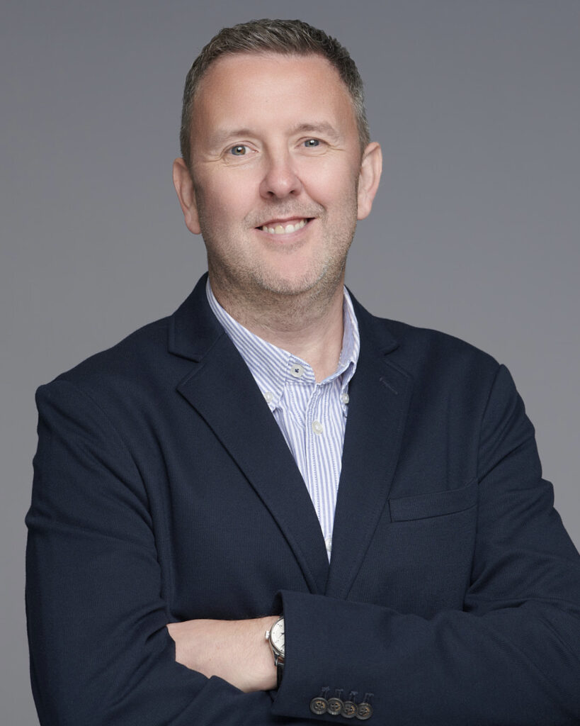 Professional business headshot of a man in a suit, photographed in London with a neutral backdrop.