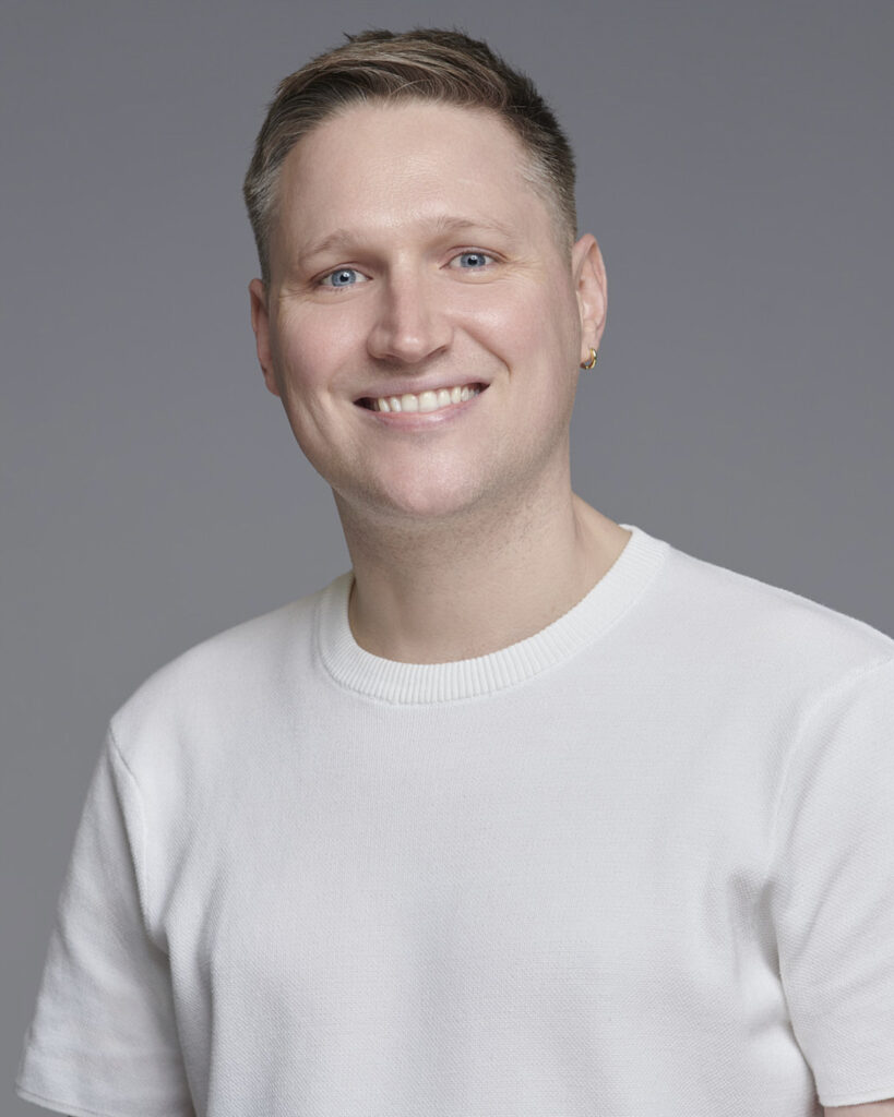 Professional business headshot of a man working in the corporate creative industry, photographed in a London studio with a neutral backdrop.