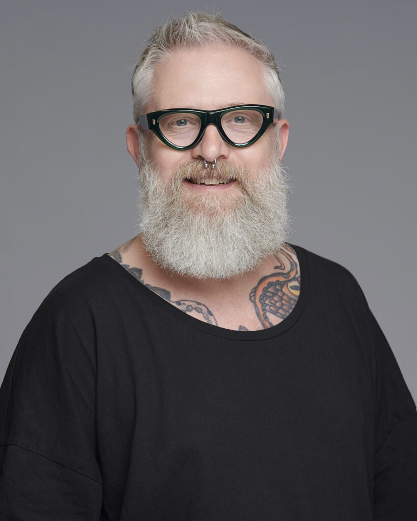 Professional business headshot of a man working in the corporate creative industry, photographed in a London studio with a neutral backdrop.