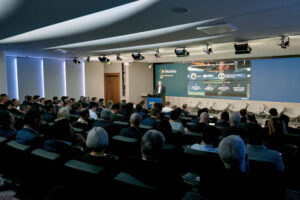 Wide shot of a large audience seated in an auditorium listening to a speaker present financial data at the Glanbia Capital Markets Day 2025