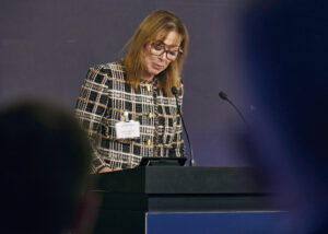 Female speaker, Patricia Mitchell, reading from a document at a dark podium during the Glanbia Capital Markets Day 2025 conference