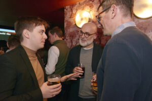 Three male attendees with glasses of beer and soft drinks engaged in conversation during the Nebula Oxygen Influencers networking reception